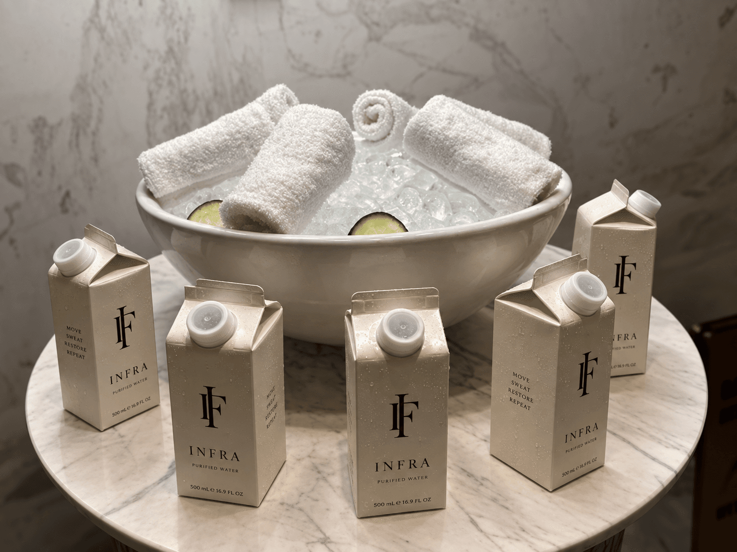 Chilled eucalyptus towels on ice with cucumber, surrounded by INFRA water cartons