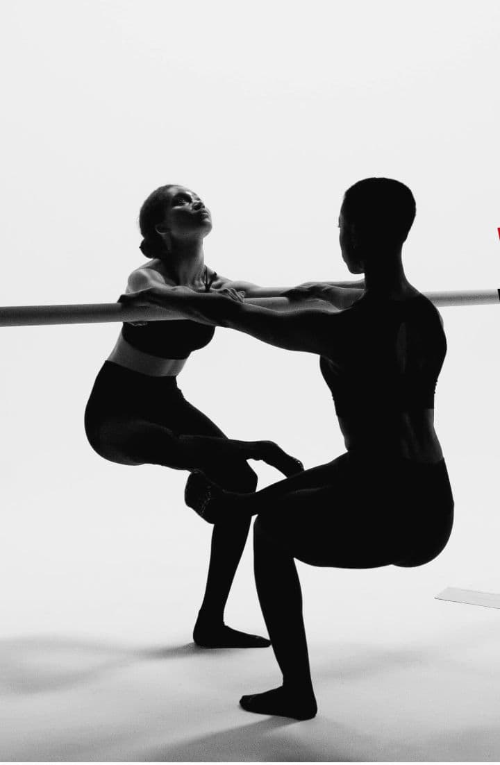 Two silhouettes stretching at the barre, clean monochrome studio light