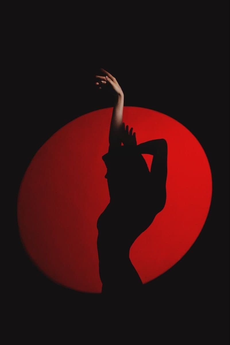 Silhouette reaching upward against a red circle of light